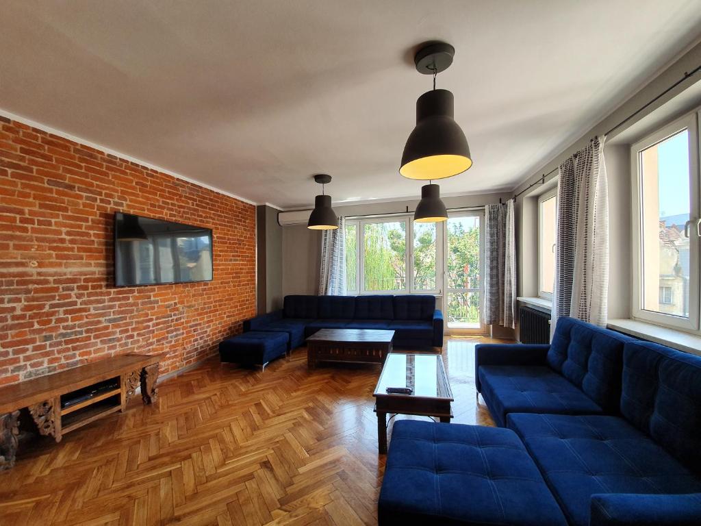 a living room with blue couches and a brick wall at Ruska61 Apart in Wrocław