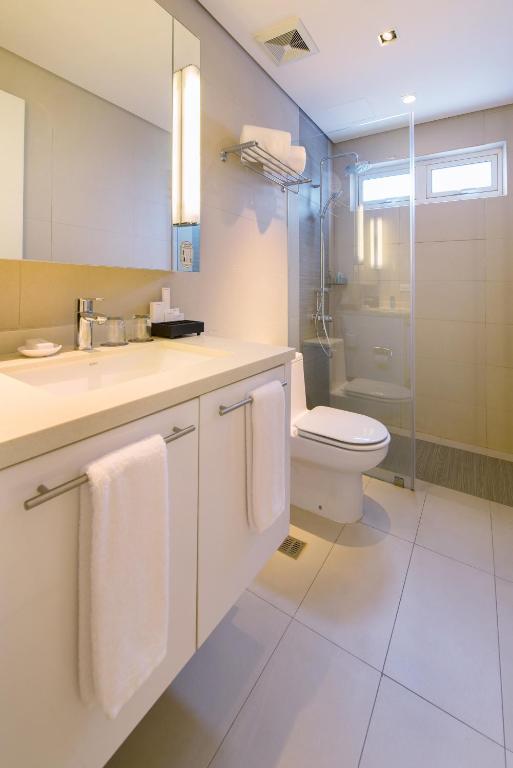 a white bathroom with a toilet and a sink at Citadines Salcedo Makati in Manila