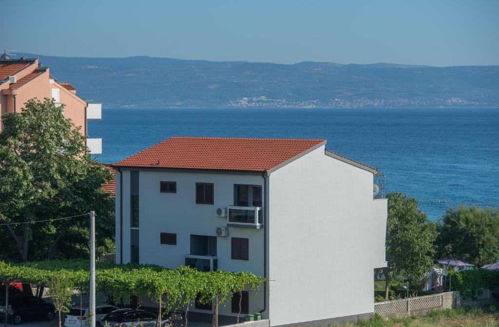 ein weißes Gebäude mit rotem Dach am Meer in der Unterkunft Apartments Vlasic in Podstrana
