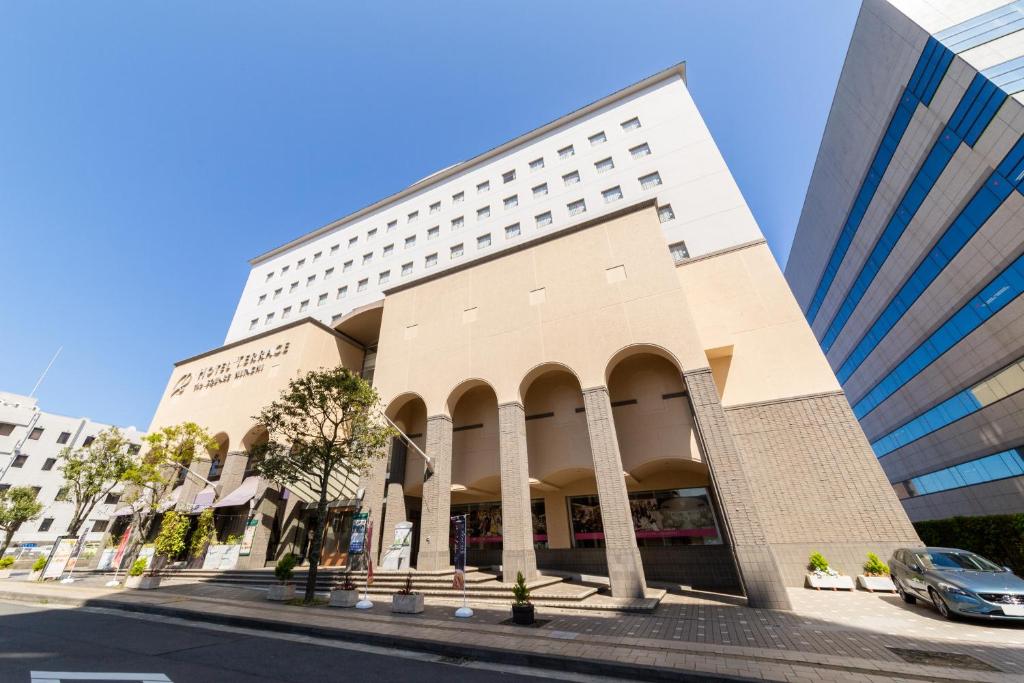 a building on a street with a car parked in front at Hotel Terrace The Square Hitachi in Hitachi