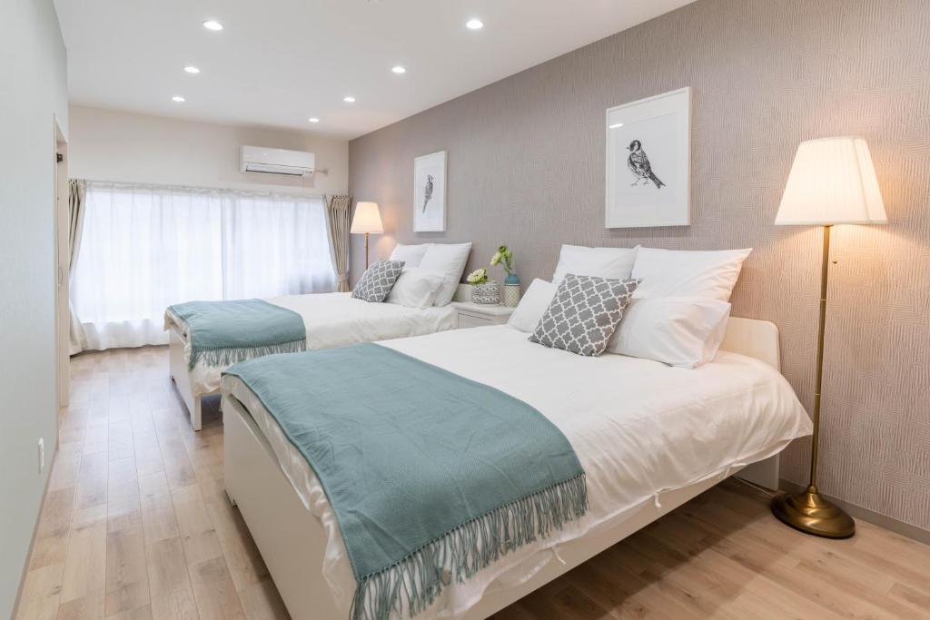 a hotel room with two beds and a lamp at Bijou Suites Cyan in Osaka