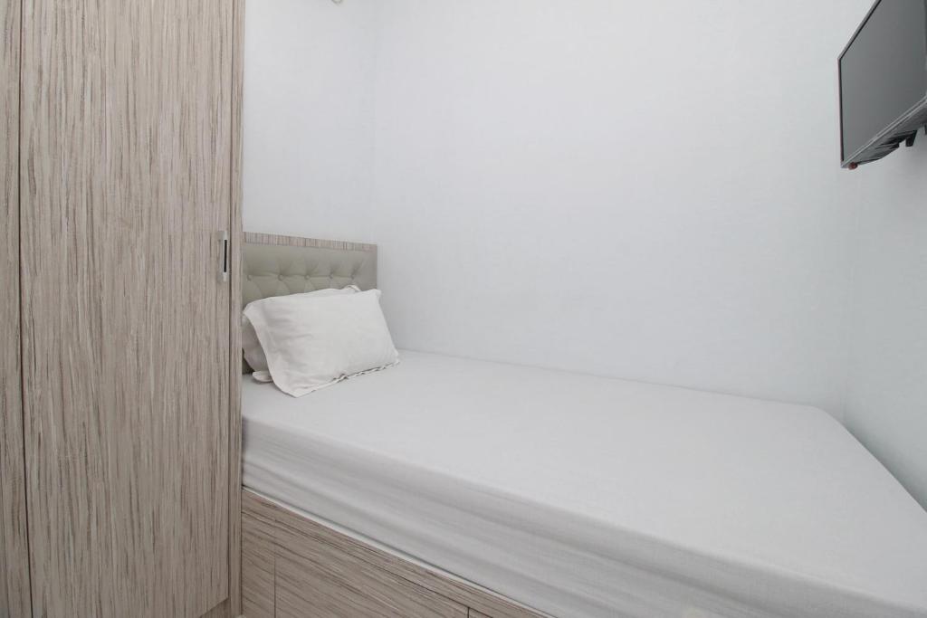 a small bedroom with a white bed and a tv at MAMA SYARIAH @ KUTAJAYA in Tangerang