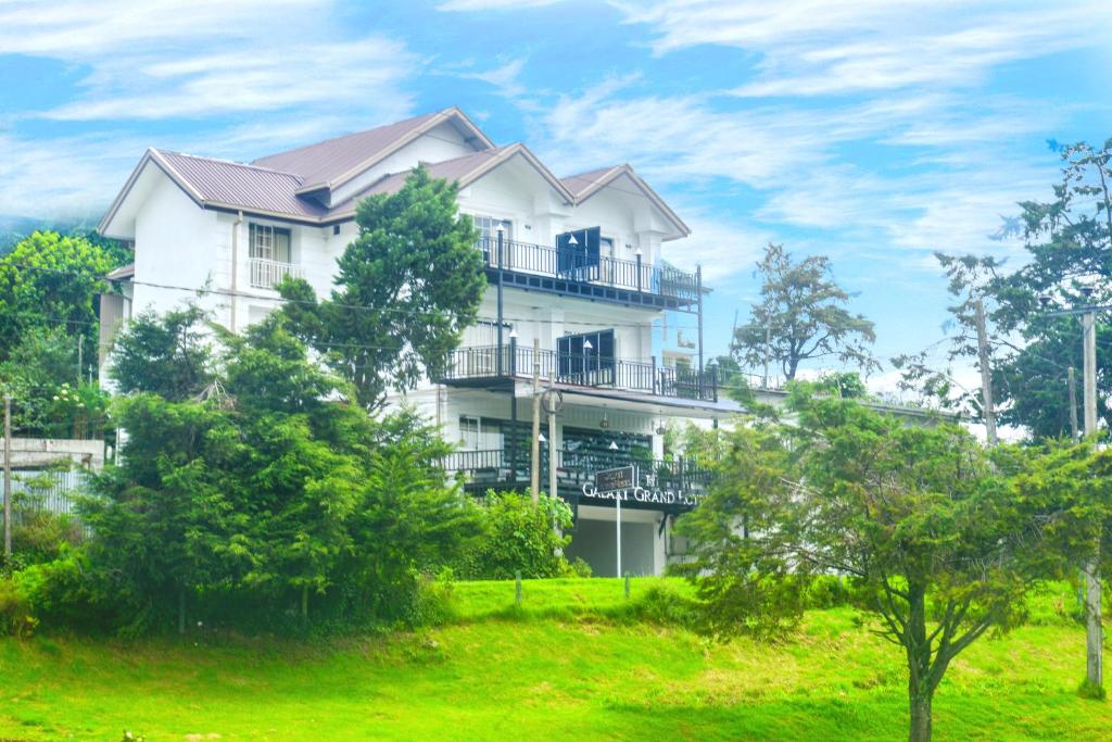 a white house on a hill with trees at Galaxy Grand Hotel in Nuwara Eliya