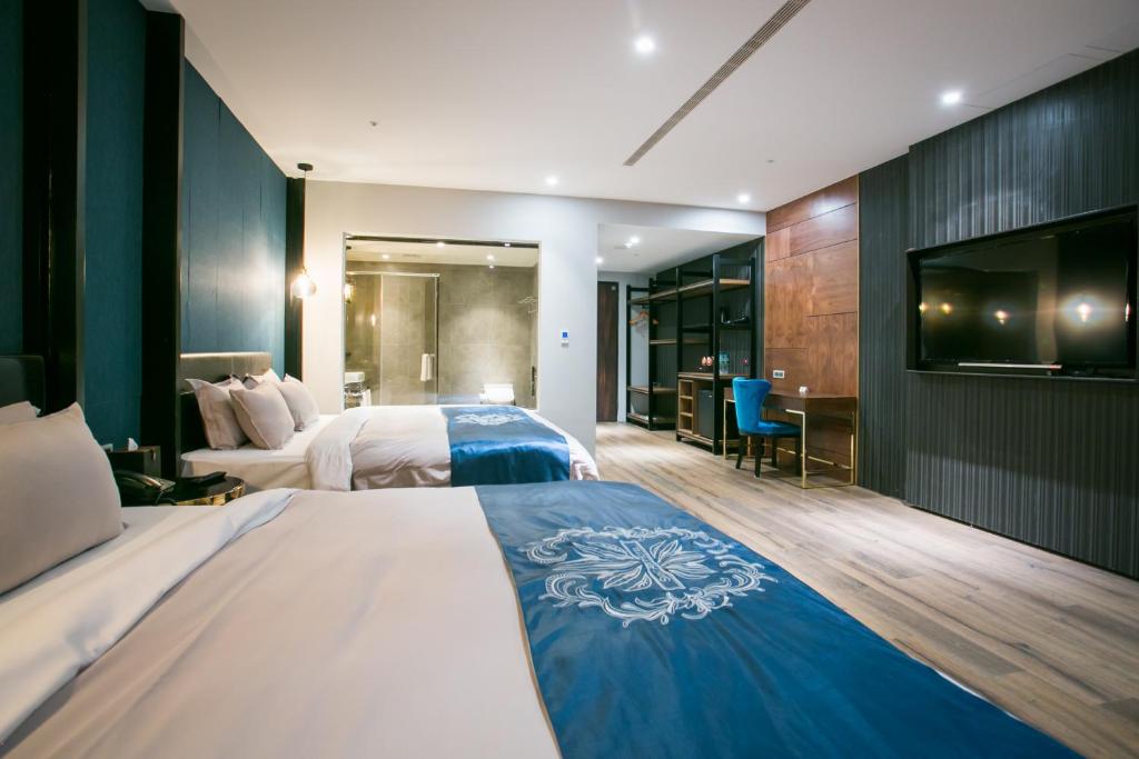 a hotel room with two beds and a flat screen tv at Saint Art Hotel in Beigang