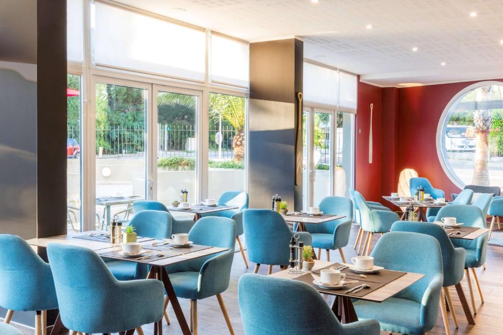 a restaurant with blue chairs and tables and windows at Best Western Plus Antibes Riviera in Antibes