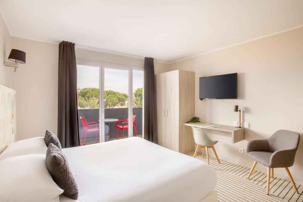 a hotel room with a bed and a desk and a window at Best Western Plus Antibes Riviera in Antibes