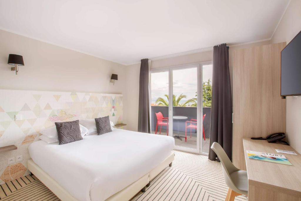 a hotel room with a bed and a desk and a window at Best Western Plus Antibes Riviera in Antibes