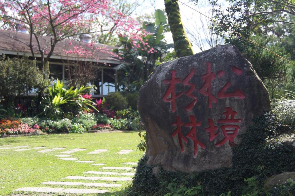 a rock with graffiti on it in front of a yard at 杉林松境休閒農場 in Nanzhuang