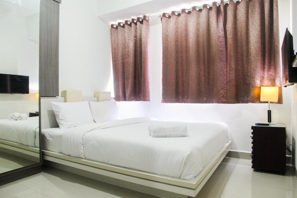 une chambre avec deux lits et une grande fenêtre dans l'établissement 1BR with Working Space The Oasis Cikarang By Travelio, à Cikarang