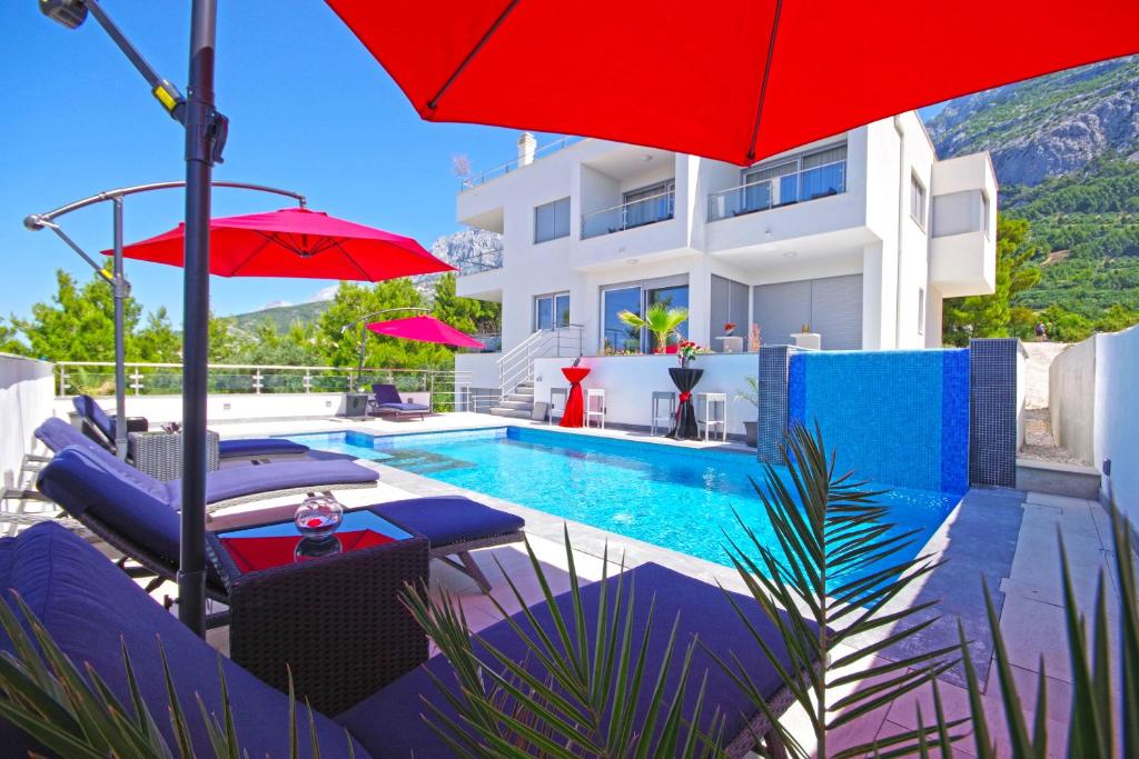 a villa with a swimming pool and a red umbrella at Villa Inis in Makarska