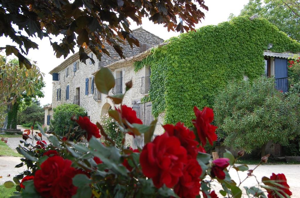 a house with red roses in front of a building at Gîte Le Gré in Chantemerle-lès-Grignan
