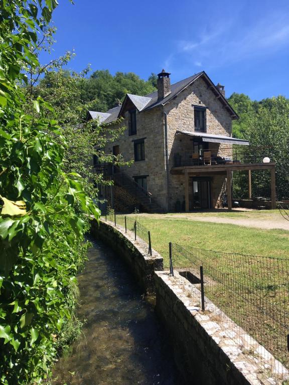una casa vieja con un río delante de ella en Au bord de l'eau, en La Canourgue