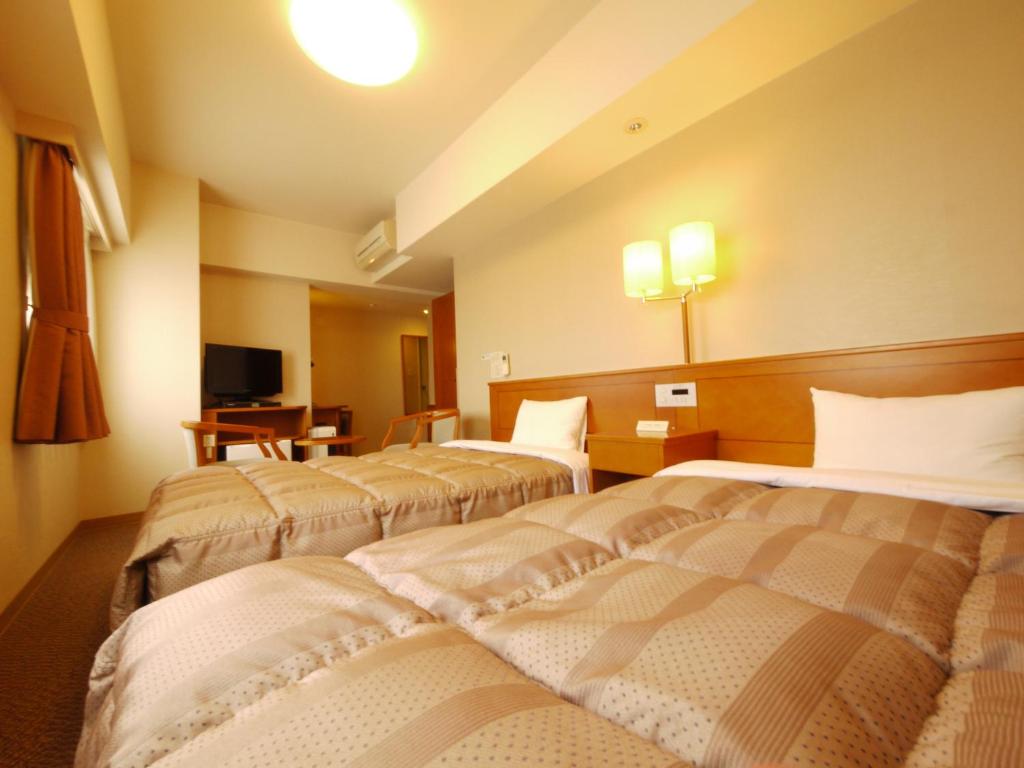 um quarto de hotel com duas camas e uma televisão em Hotel Route-Inn Fukaya Ekimae em Fukaya