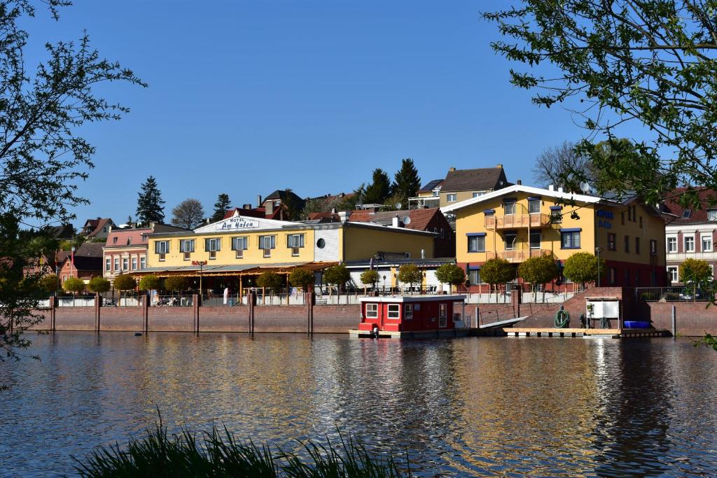 a river with houses and a red boat in the water at Hotel garni "Am Hafen" in Havelberg