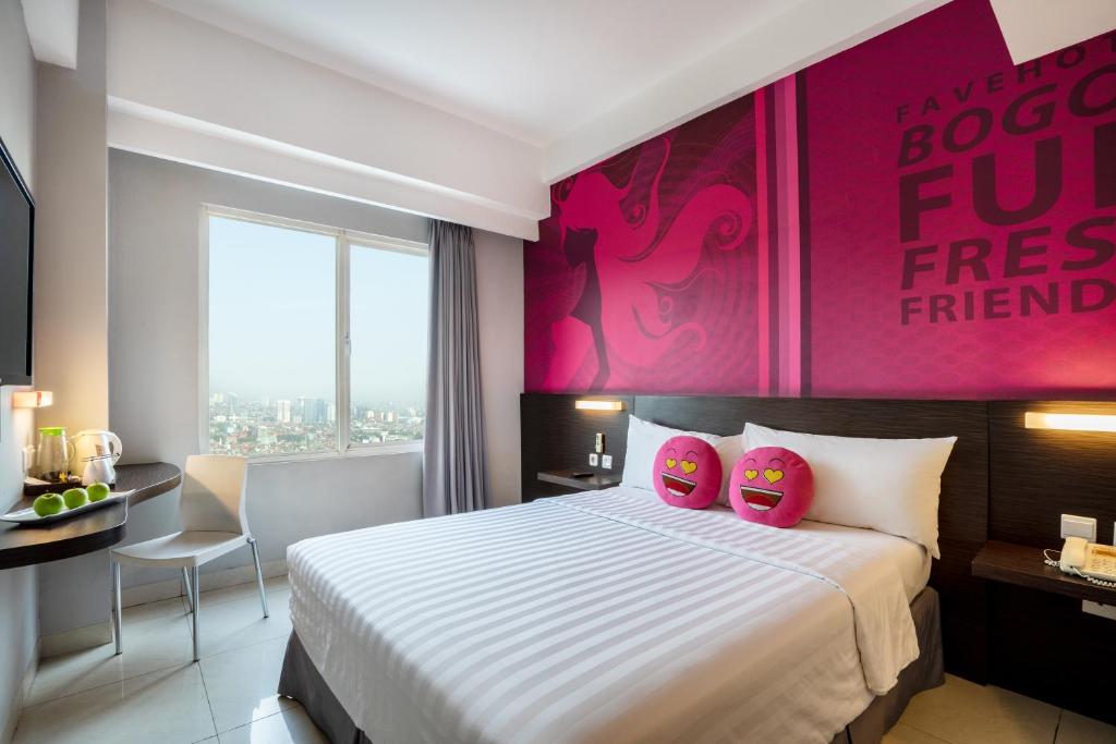 Habitación de hotel con cama y pared de color rosa en favehotel Padjajaran Bogor en Bogor