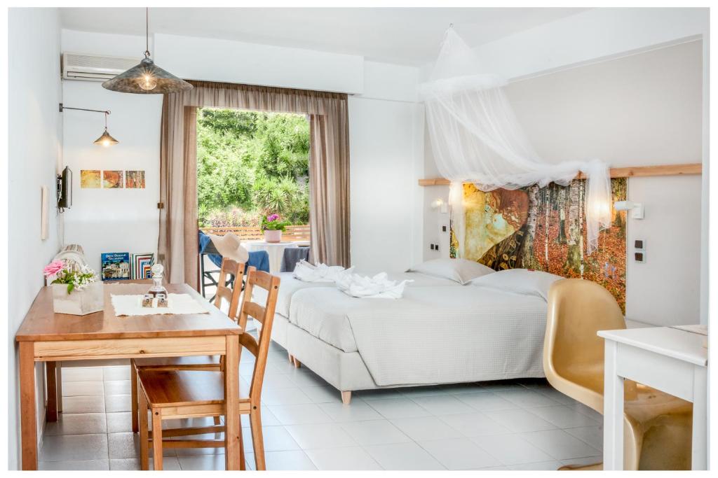 a white bedroom with a bed and a table at Tree of Life Art Hotel in Agia Marina Nea Kydonias