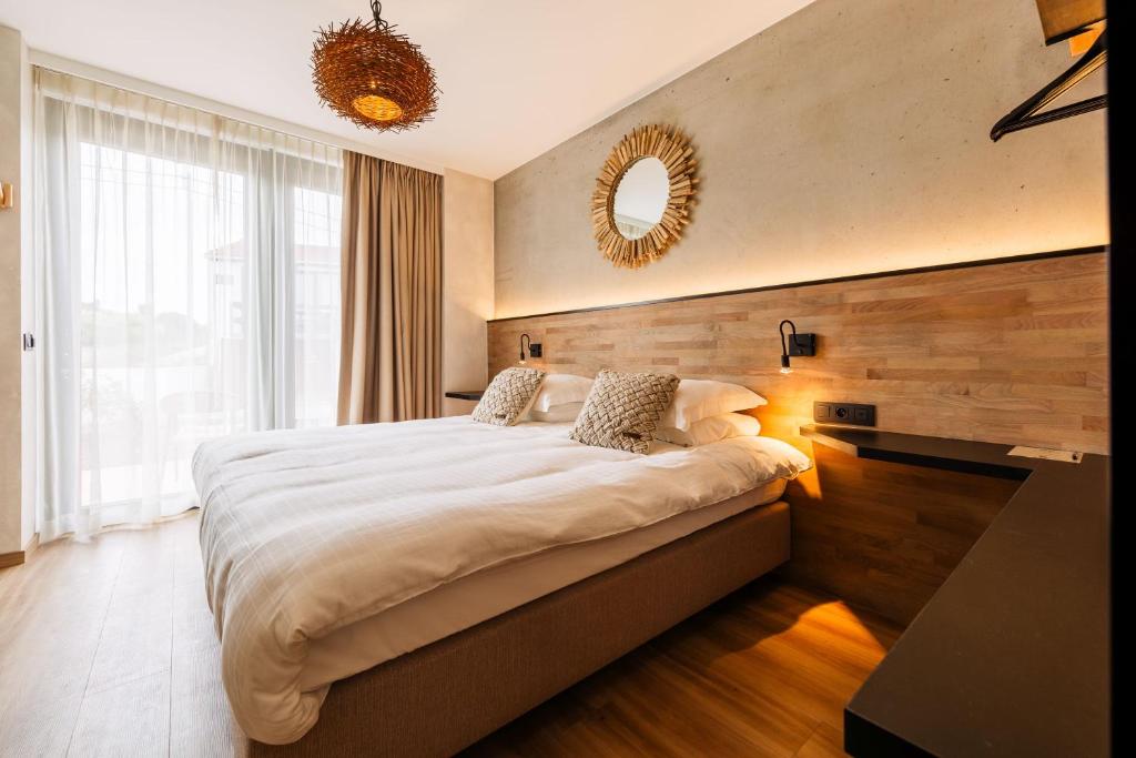 a bedroom with a large bed and a mirror at C-Hotels Zeegalm in Middelkerke