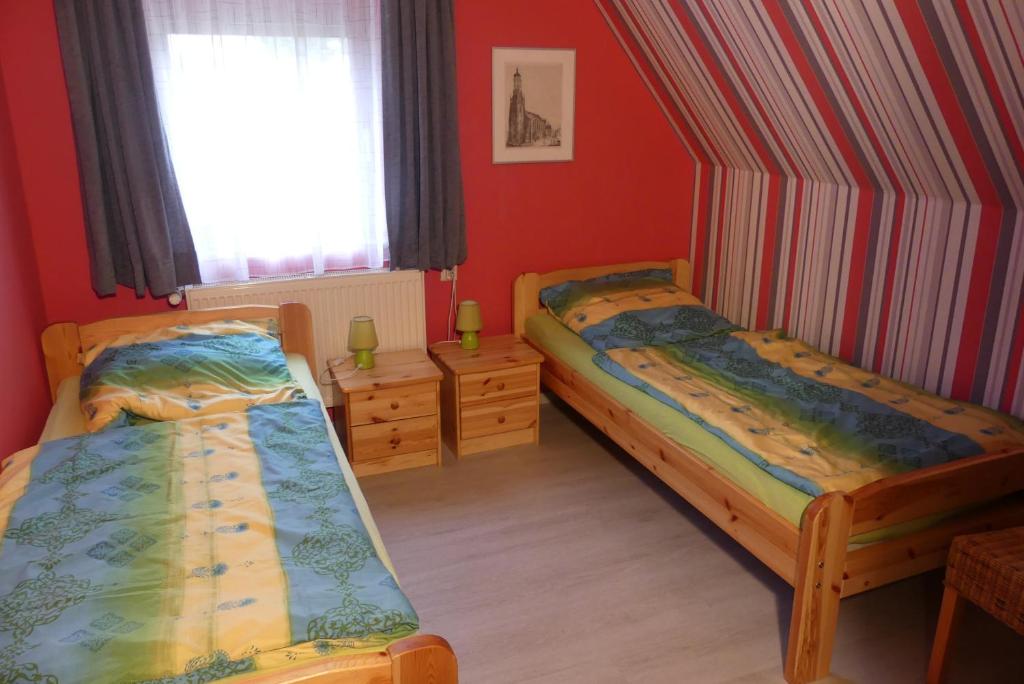 due letti in una stanza con pareti rosse e una finestra di Ferienwohnung Irmgard a Nördlingen