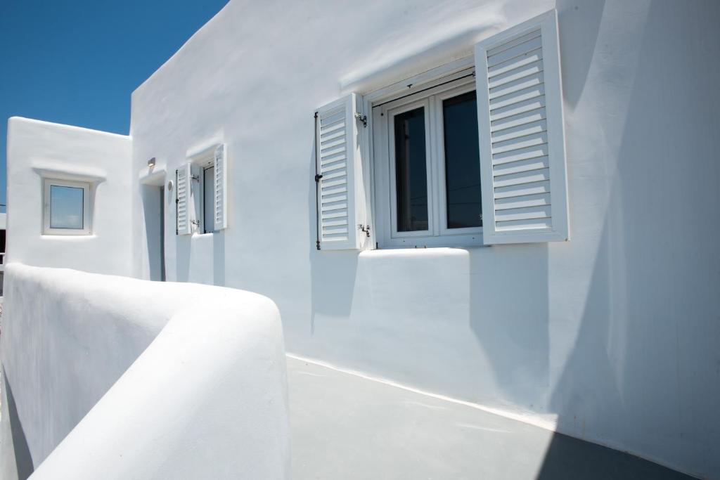 un edificio blanco con persianas blancas y una ventana en Bleland Mykonos II en Ano Mera