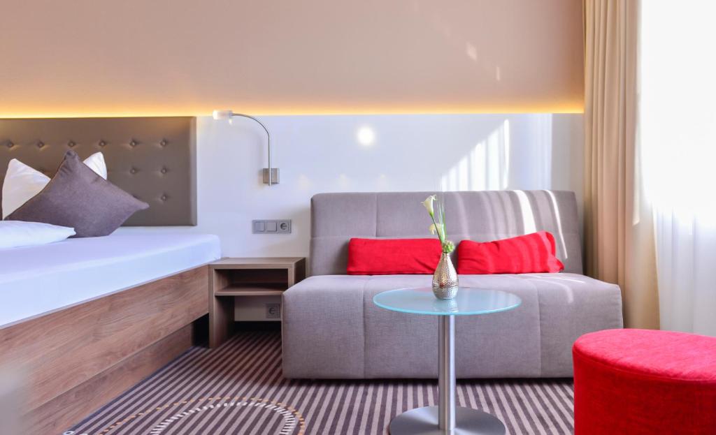 um quarto com uma cama, um sofá e uma mesa em Hotel Fuchsen em Kirchheim unter Teck