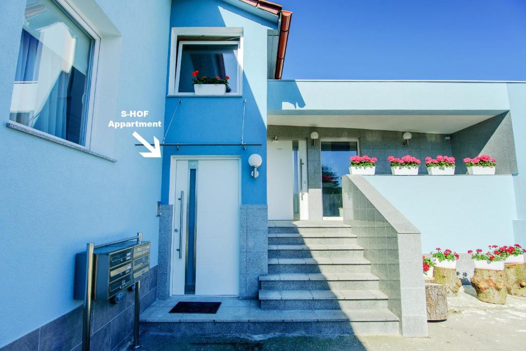 uma casa azul com escadas e vasos de plantas em S-HOF Appartment em Sonnenbühl