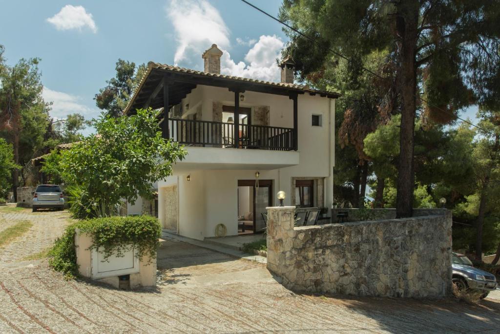 a large white house with a stone wall at Izabella Sea Side Villa in Siviri