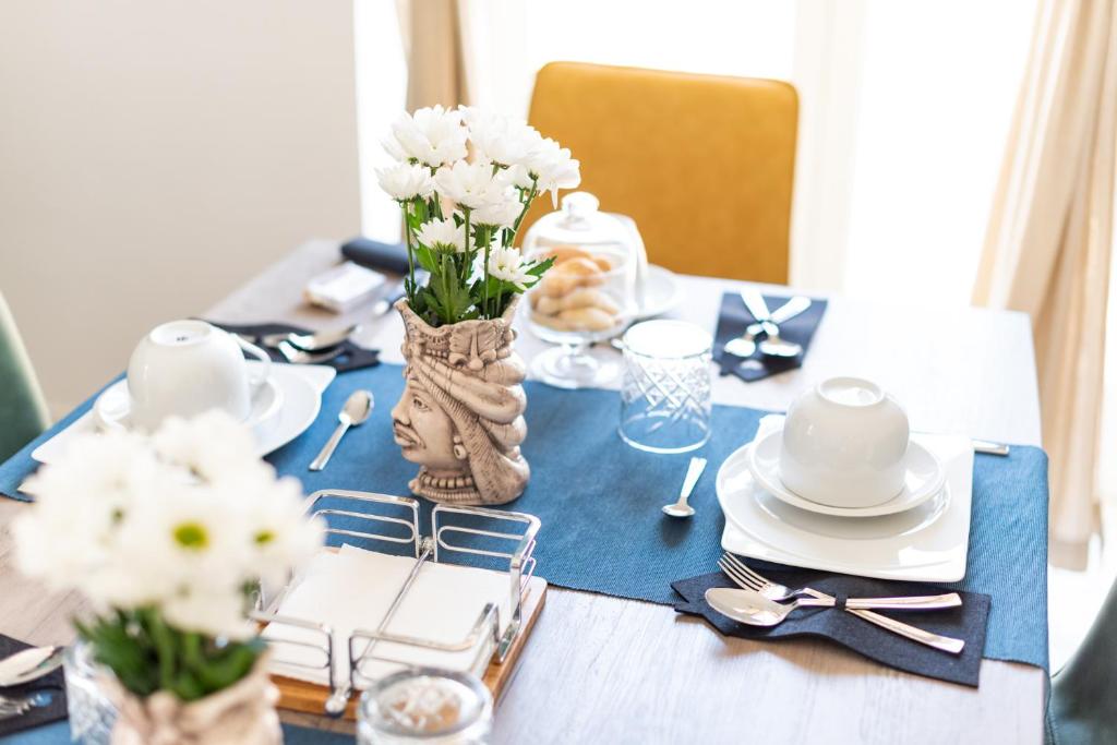 uma mesa com uma toalha de mesa azul e flores brancas em A casa di Cassi em Modica