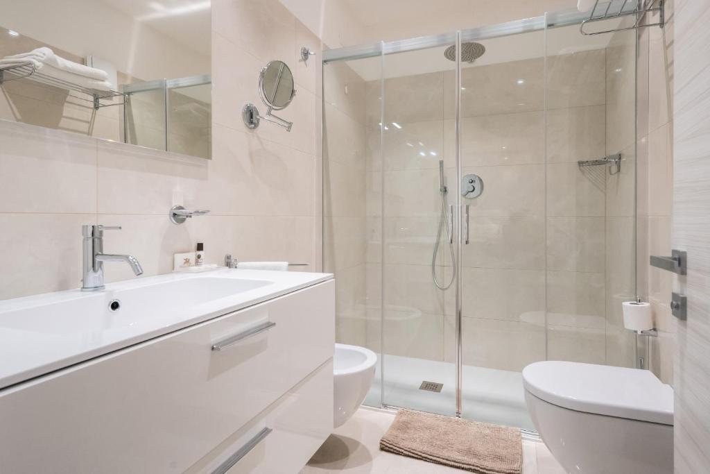 a white bathroom with a sink and a shower at International Beach Hotel in Caorle