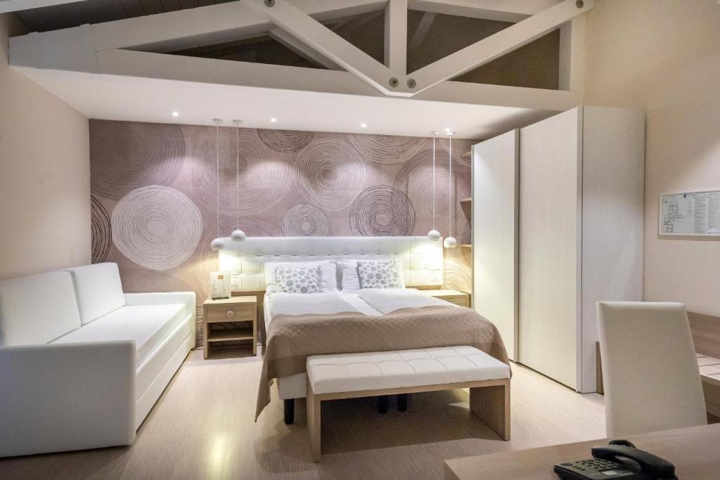 a bedroom with a white bed and a couch at International Beach Hotel in Caorle