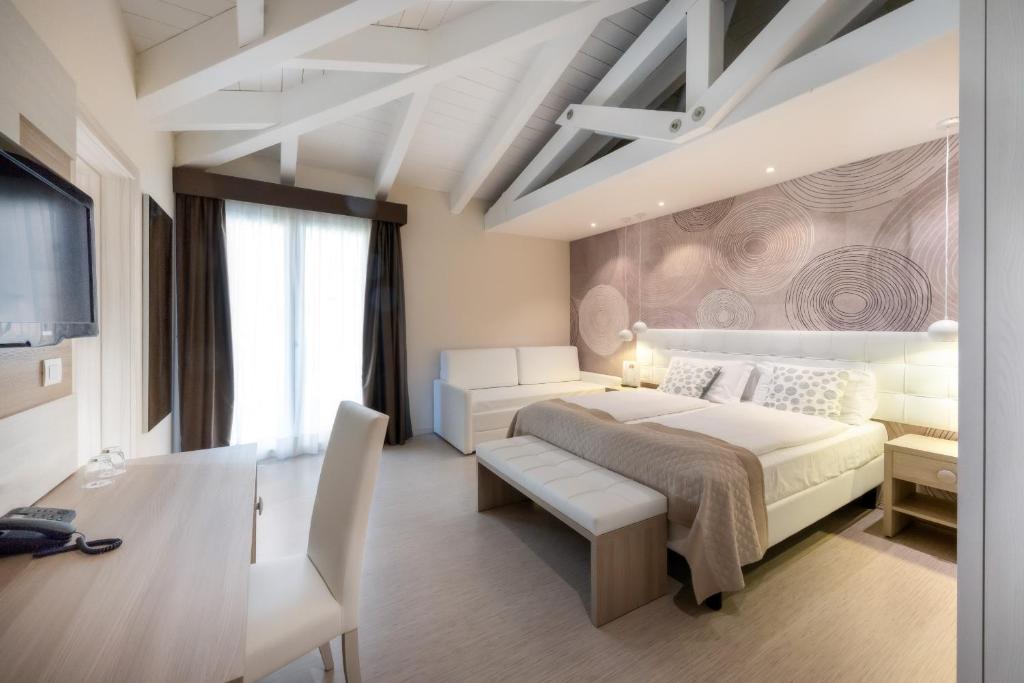 a bedroom with a large white bed and a desk at International Beach Hotel in Caorle