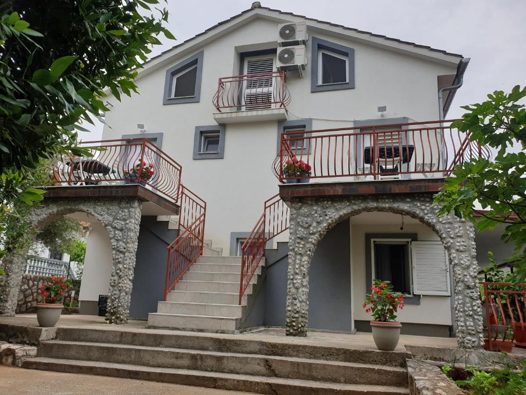 a white house with red balconies and stairs at Apartmani Pejo in Gostinjac