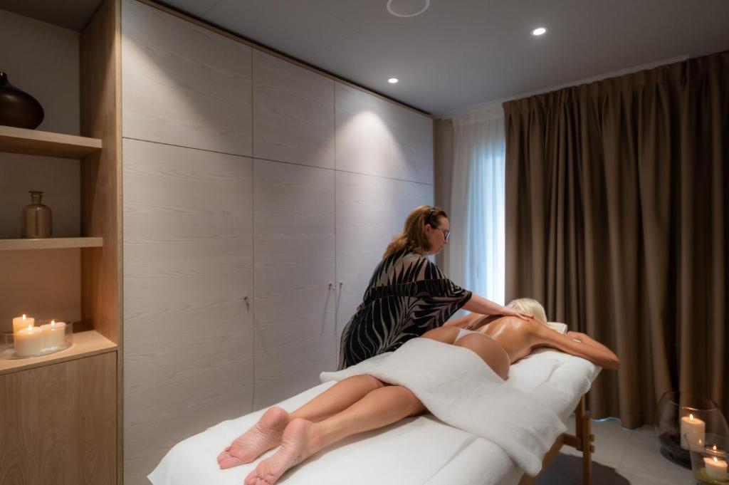 a woman sitting on a bed with a woman sitting on top of it at International Beach Hotel in Caorle