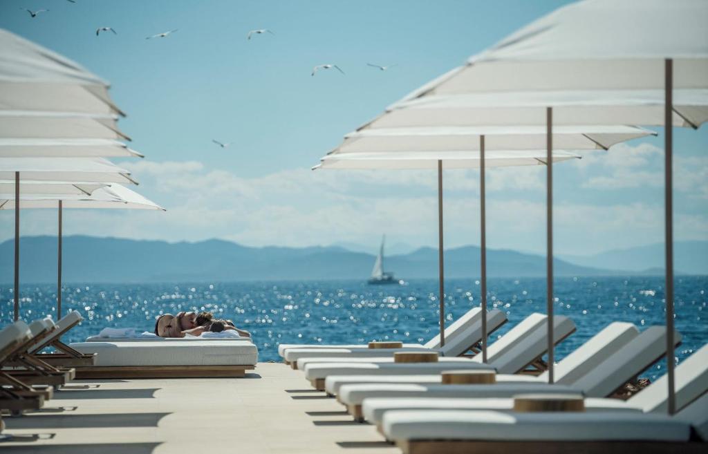 eine Reihe von Liegestühlen und Sonnenschirmen am Strand in der Unterkunft Four Seasons Astir Palace Hotel Athens in Athen