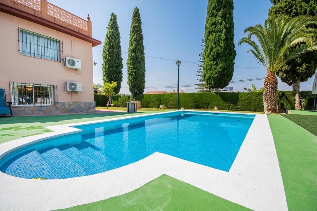 a swimming pool in front of a house with trees at Cubo's Casa Los Mimbrales in Alhaurín de la Torre