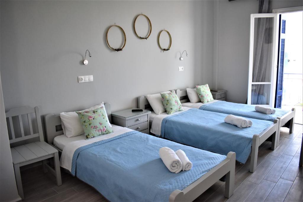 1 dormitorio con 3 camas, silla y espejos en Aphrodite Art Hotel Aegina, en Aegina Town