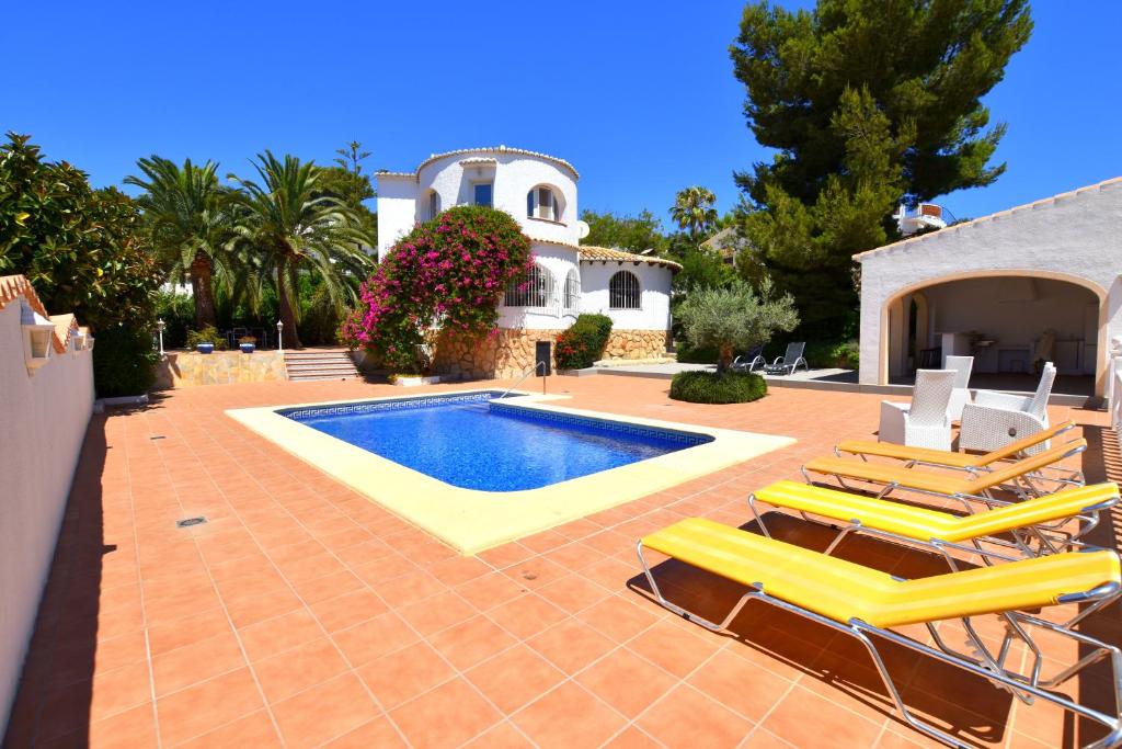 una piscina con sillas y una casa en Casa Alto, en Jávea