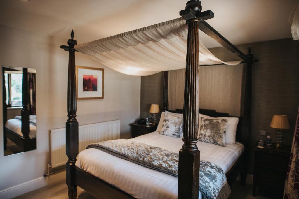 a bedroom with a four poster canopy bed at Hall Farm Hotel And Restaurant in Ashby cum Fenby