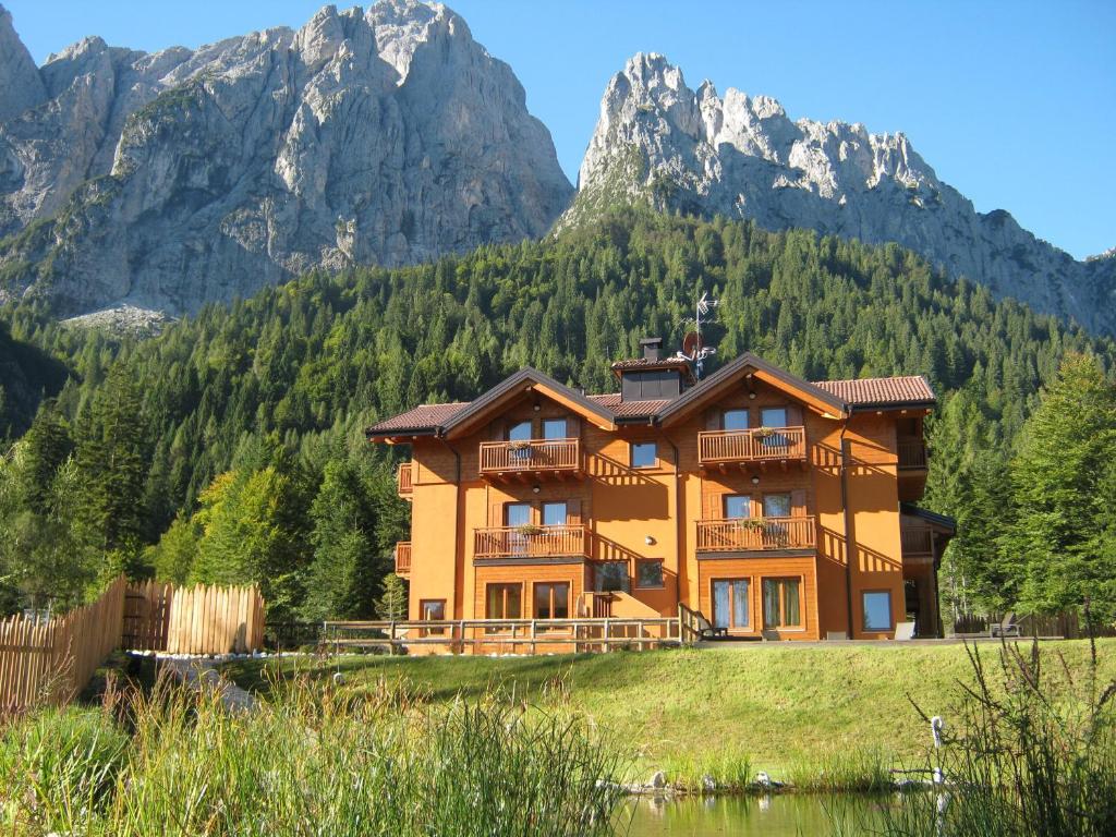 ein großes Haus mit Bergen im Hintergrund in der Unterkunft Hotel Chalet Giasenei in Sagron Mis