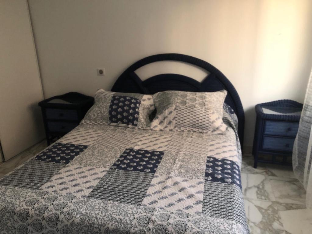 a bed with a blue and white blanket and pillows at T2 DE 40 M2 EN REZ DE JARDIN Avec parking CARNON PLAGE in Mauguio
