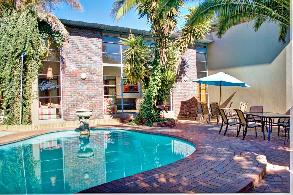a swimming pool with chairs and a table with an umbrella at African Moon Corporate House in Kempton Park