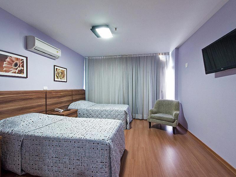 una habitación de hotel con 2 camas y una silla en Gallant Hotel, en Río de Janeiro