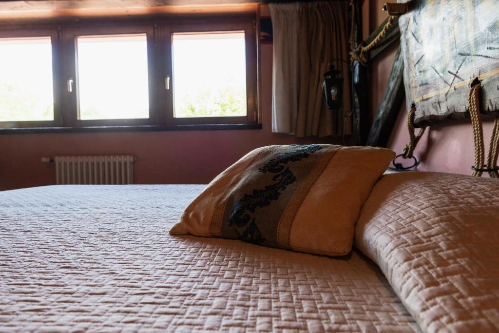 a bed with a pillow on it with two windows at Agriturismo Mezzaluna in Málchina