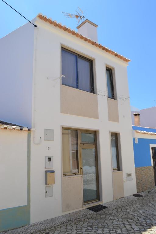 a white house with glass doors on a street at Casa Madalena in Barão de São João