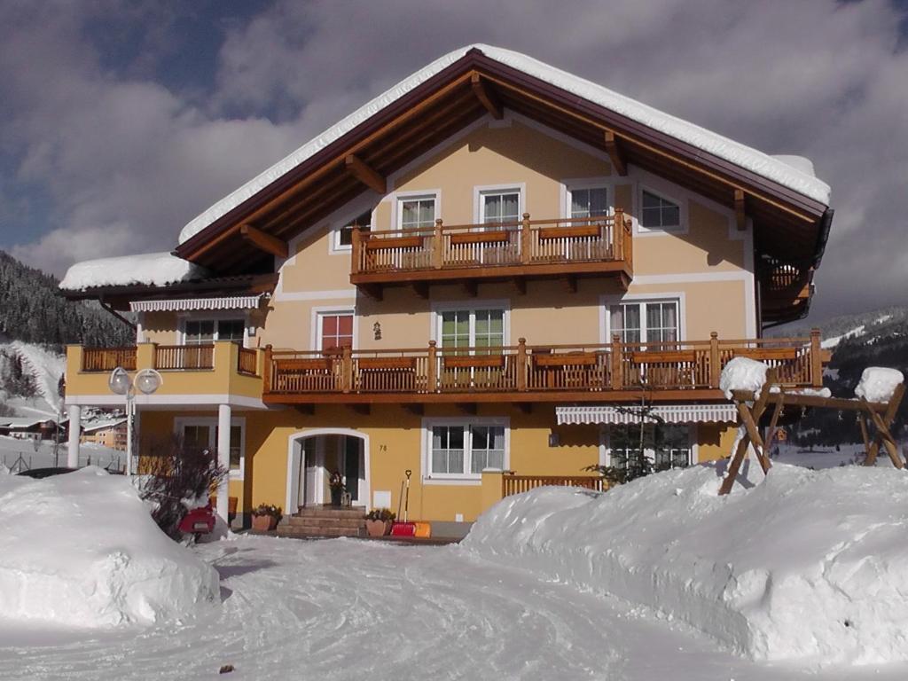 uma grande casa com uma varanda numa pista de esqui em Haus Maier em Flachau