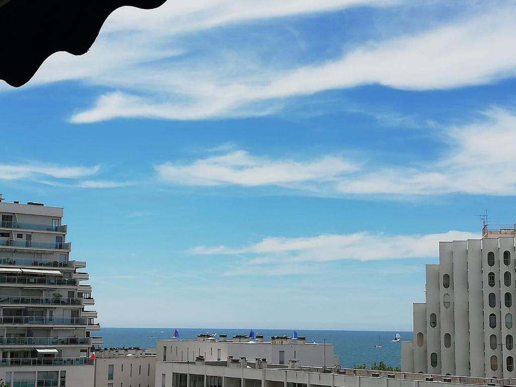 einen Blick auf Gebäude und einen blauen Himmel mit Wolken in der Unterkunft Le Sémaphore - studio climatisé, grande terrasse vue mer - parking, wifi in La Grande-Motte