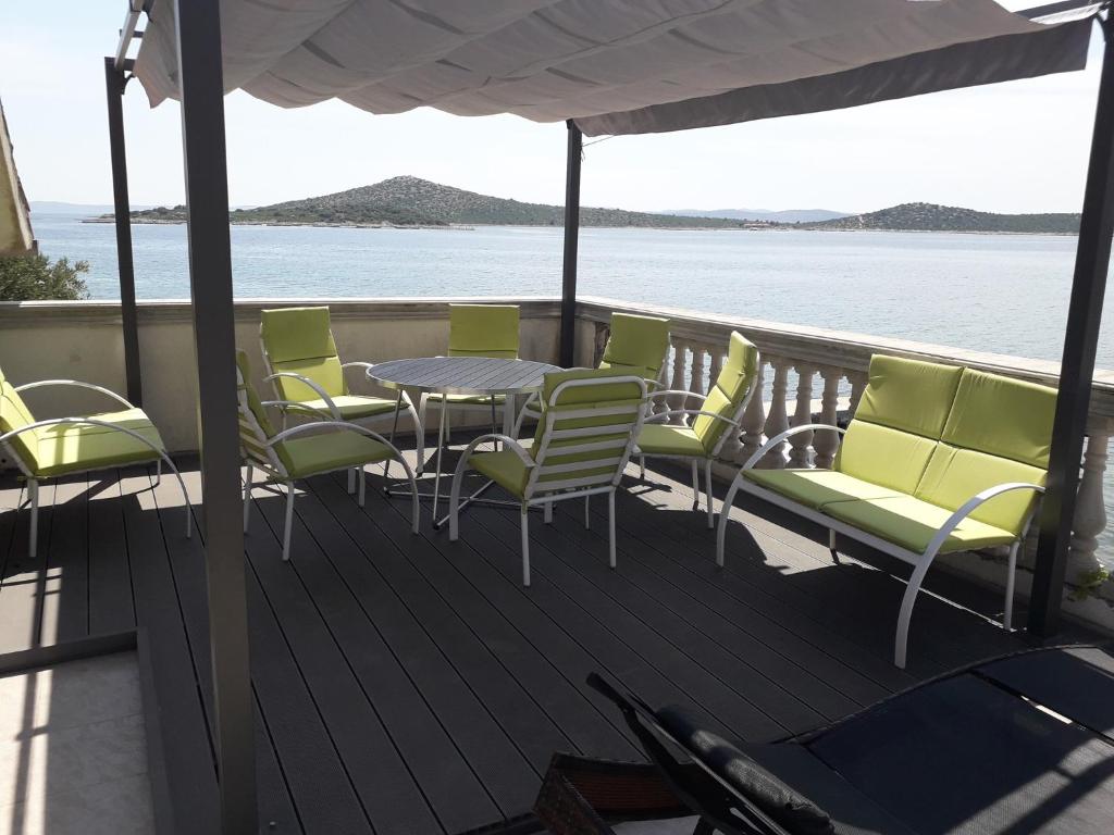 a deck with a table and chairs and the water at Holiday House Val with sea view in Pašman