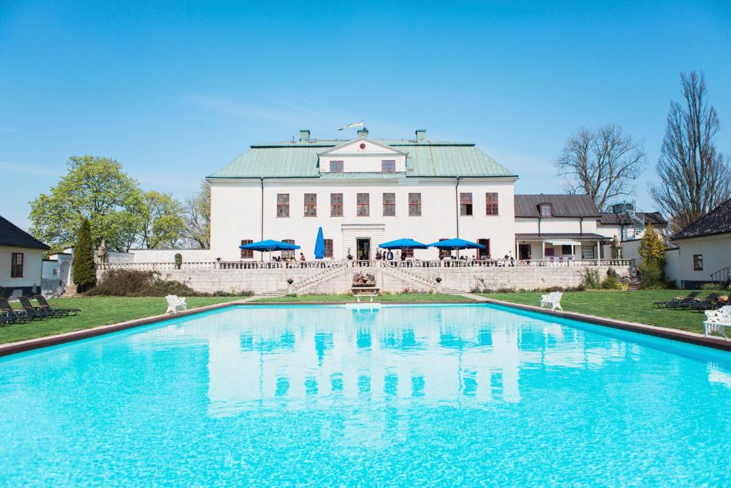 a large swimming pool in front of a large white building at Häringe Slott in Västerhaninge
