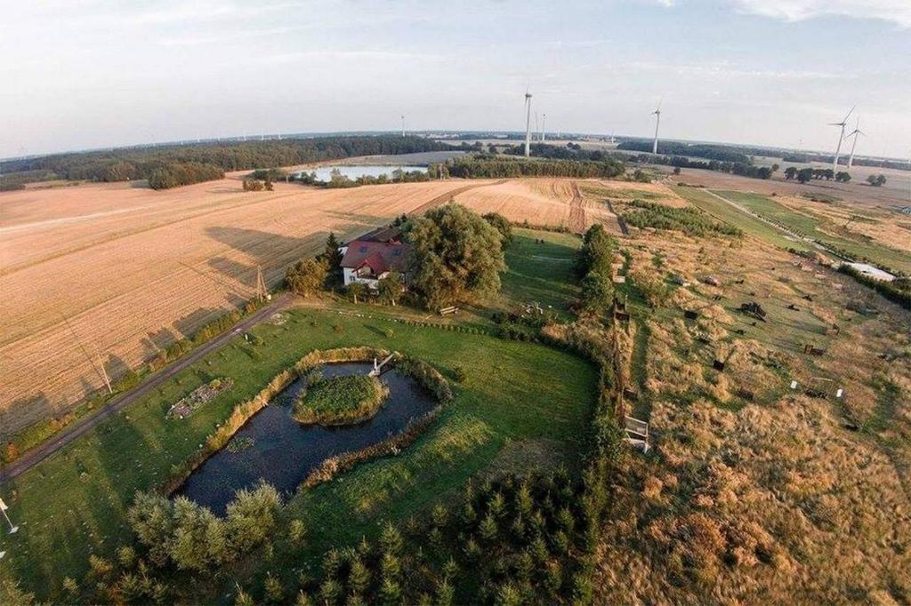 an aerial view of a house and a pond in a field at Ranczo u Stefana in Ustronie Morskie