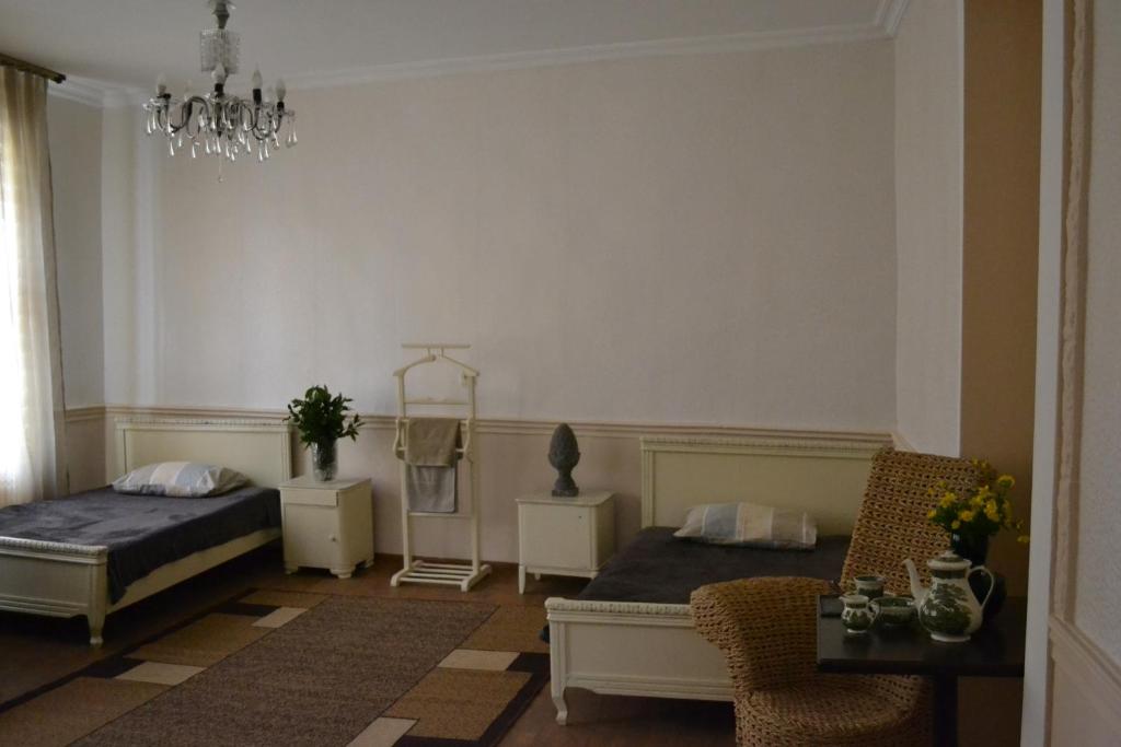 a bedroom with two beds and a chair and a chandelier at Guest house Amazon in Kutaisi