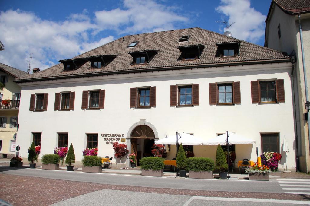 ein weißes Gebäude mit braunem Dach in der Unterkunft Gasthof Sonne in St. Lorenzen